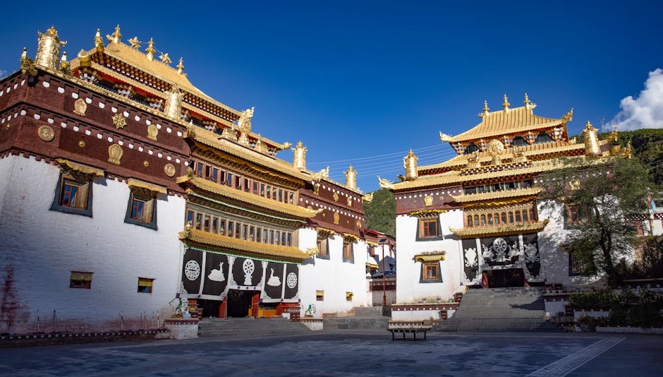 Beautiful Tibetan monastery with ornate golden roofs under a clear blue sky.